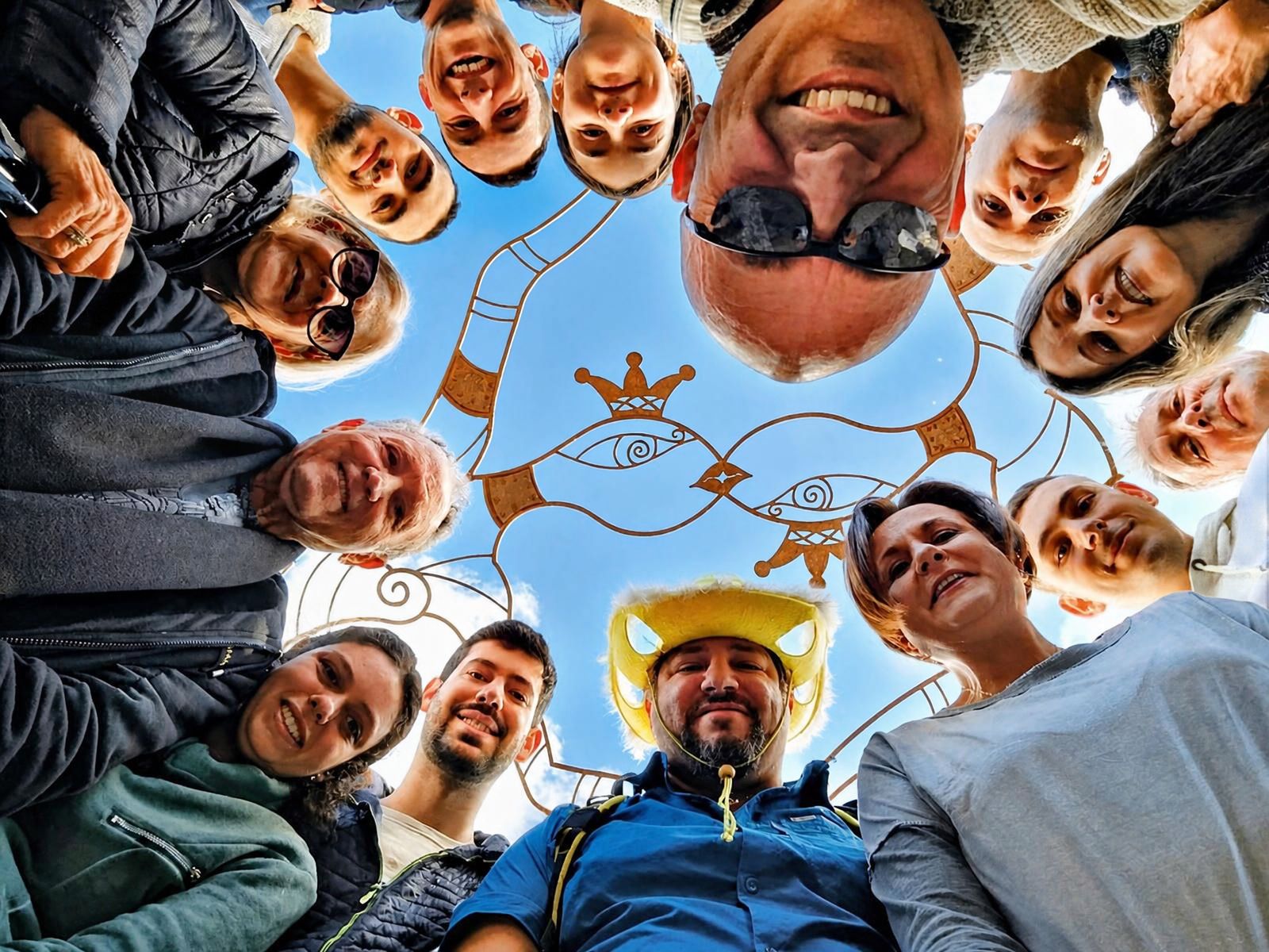 סלפי קבוצתי במעגל מתחת לפסל ברזל עם הכובע הצהוב
