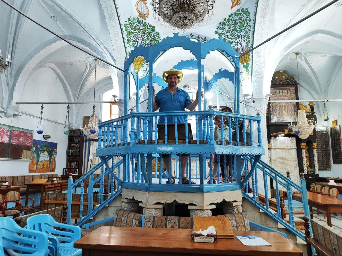 המדריך עם הכובע הצהוב על הבימה הכחולה בבית כנסת בצפת