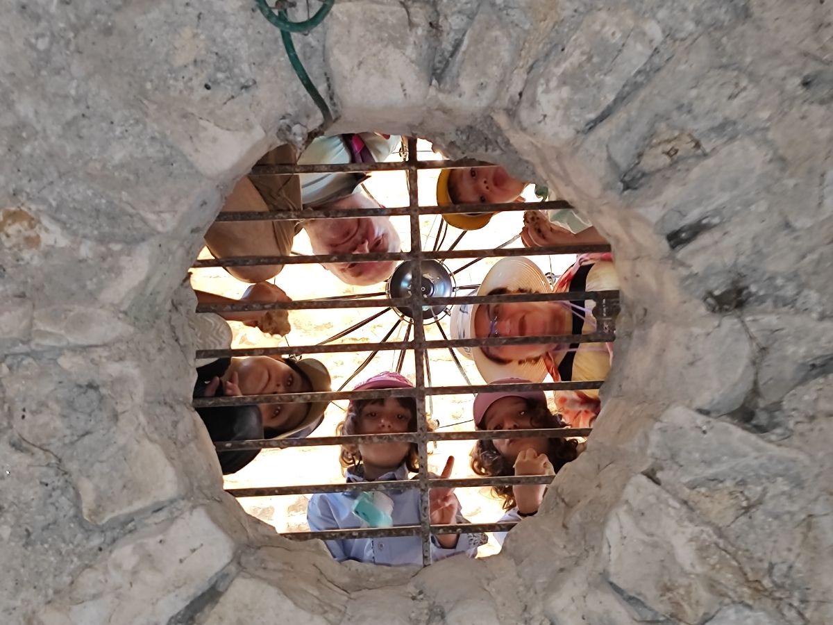 פרצופים מחייכים מבעד לחלון אבן עגול בצפת