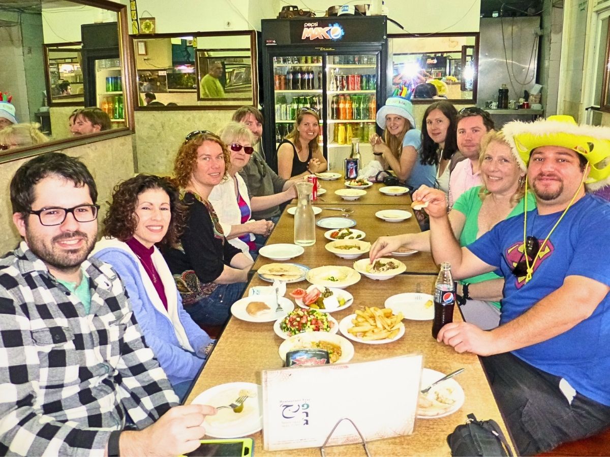קבוצת מטיילים סביב שולחן ארוך עם טעימות כשרות במסעדה בעיר התחתית של חיפה