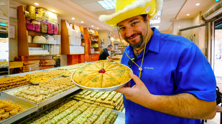 דניאל עם הכובע הצהוב ומגש באקלווה בחנות מתוקים
